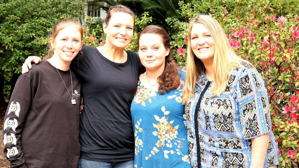 Women from the Savannah Mission faith-based recovery program standing together among the azaleas